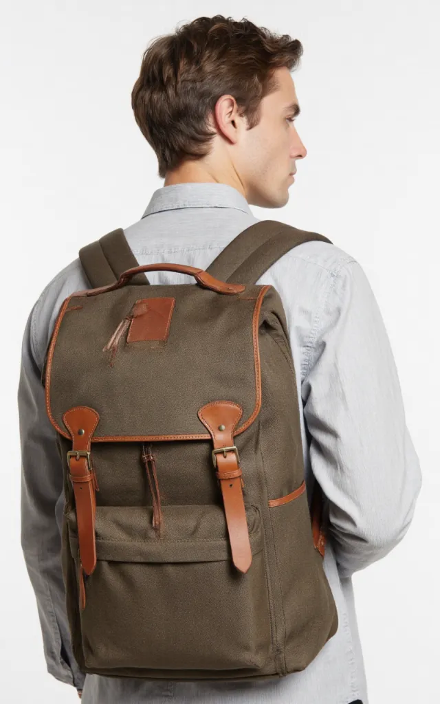 A French male model with a Leather   trimmed canvas backpack, wearing a shirt, against a white background, in a front   facing close   up